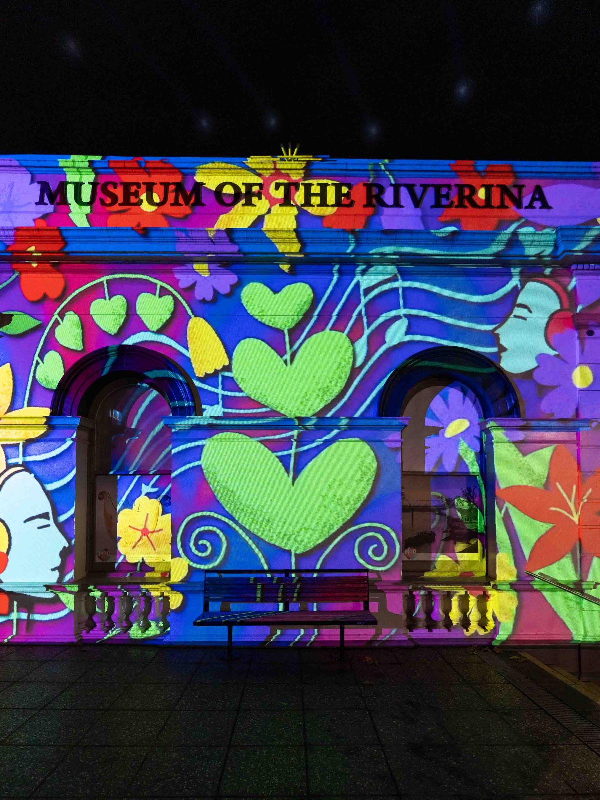 A projection of light and colour on the façade of the Museum of the Riverina Historic Council Chambers at night-time during Festival of W