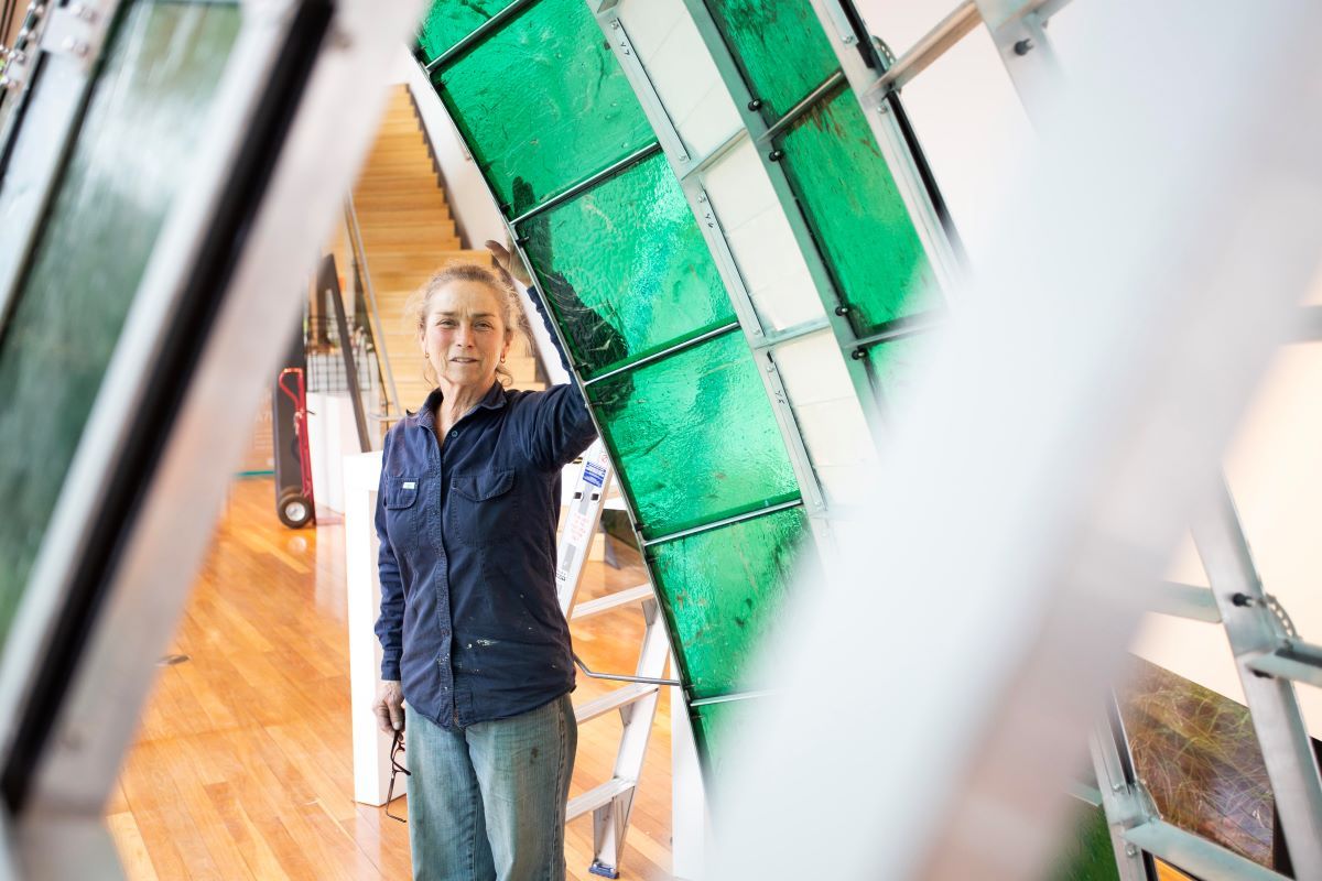 a woman standing with her large glass and metal sculpture. 