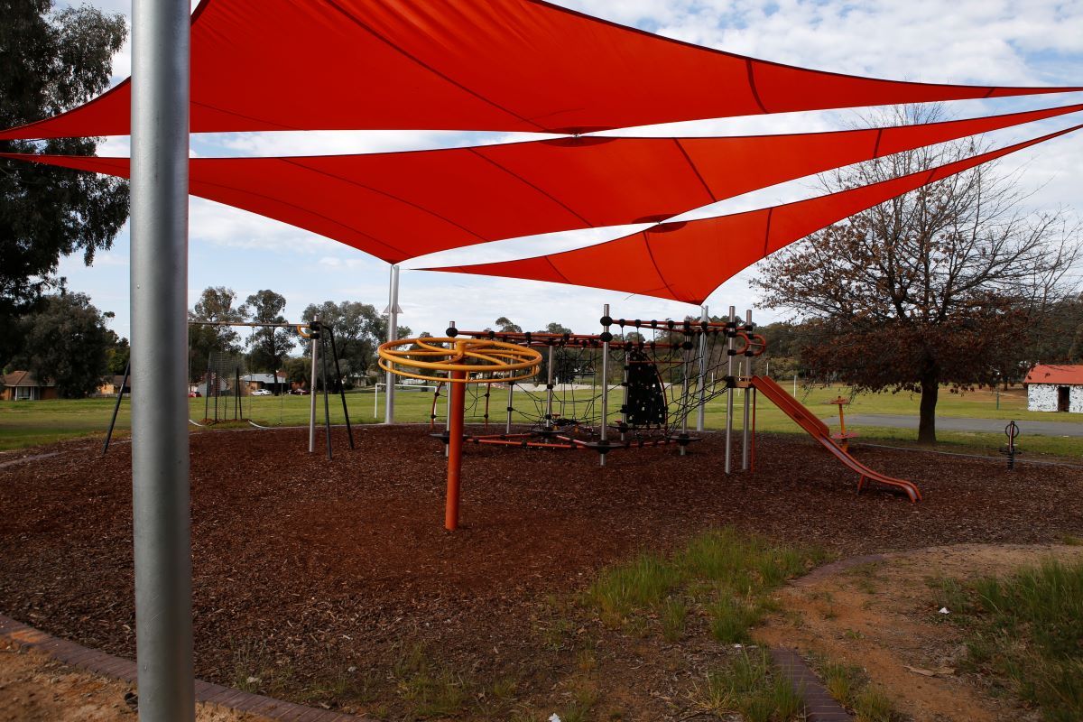 Some bright orange shade sails over an outdoor playground. 