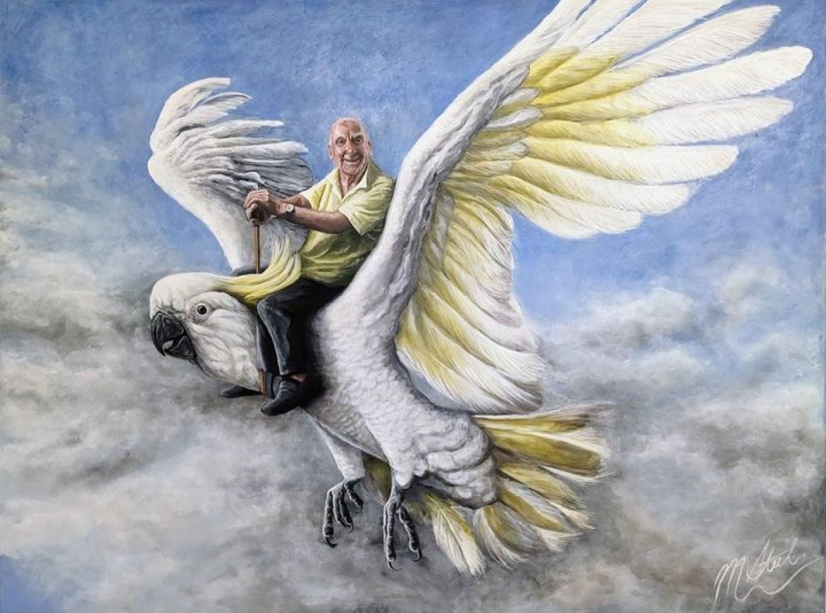 Portrait of man sitting on back of a flying white cockatoo.