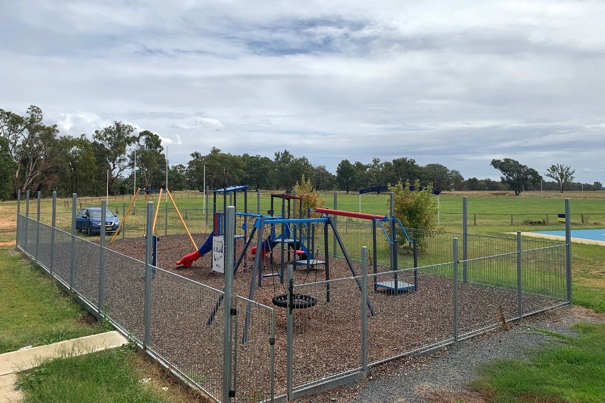 Playground surrounded by fence, located next to Australian Rules football ground