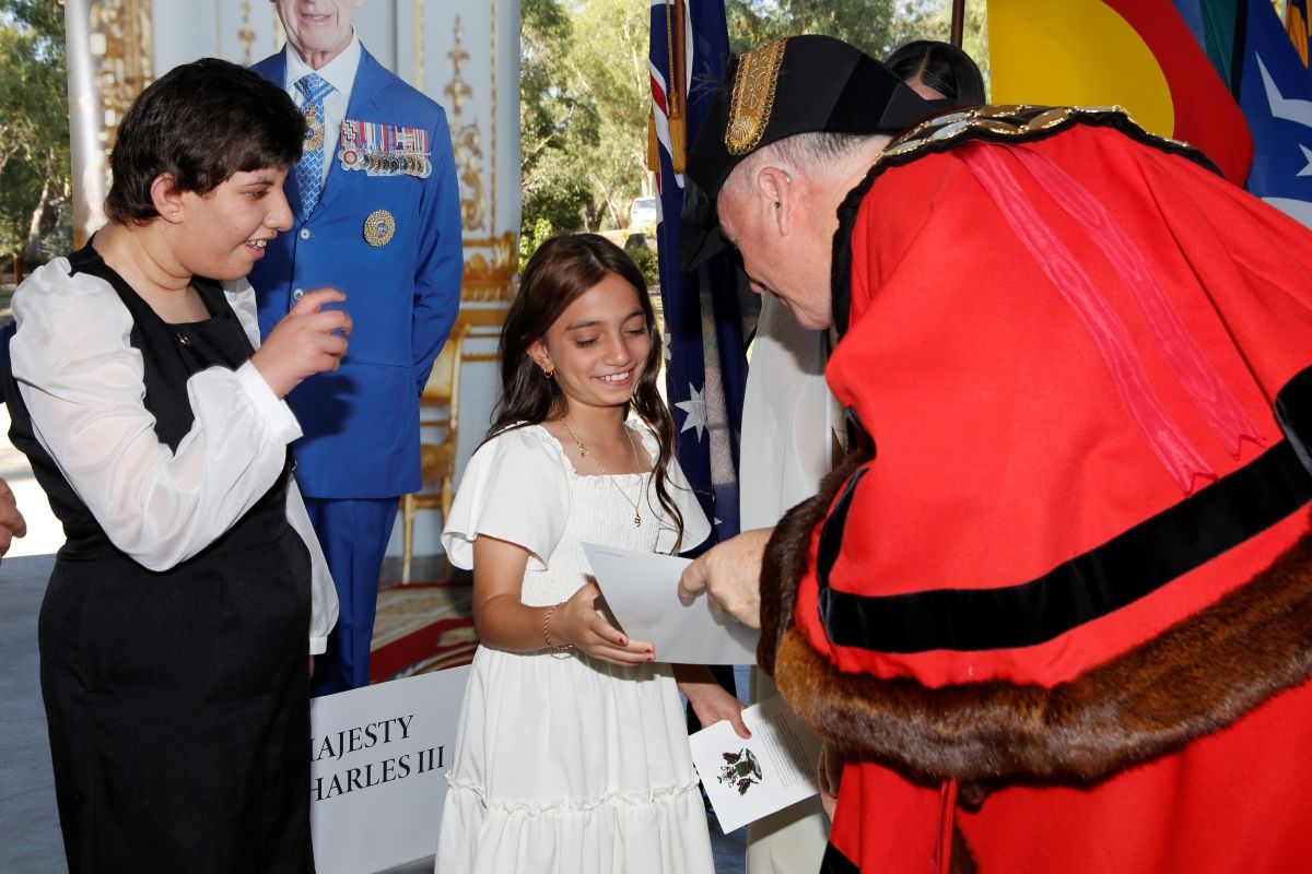 The mayor hands a certificate to a smiling citizen.