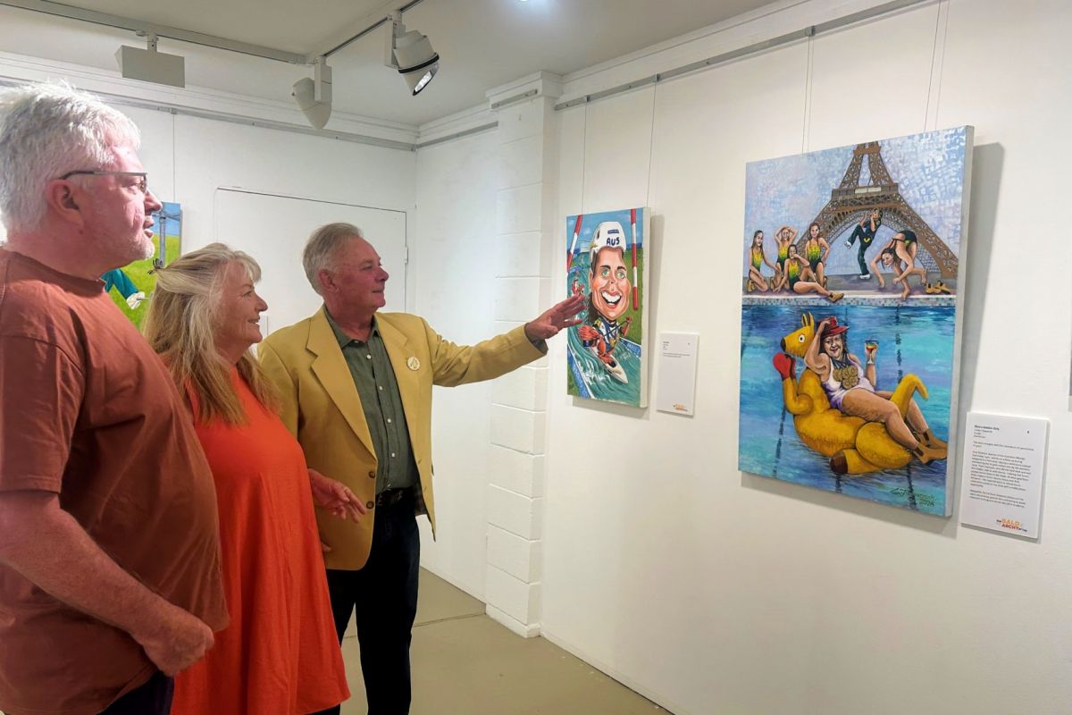 Two men and a woman standing in an art gallery looking at a colourful and satirical portrait depicting Gina Rinehart in a swimsuit on a floating kangaroo with Australian Olympic swimmers in the background underneath the Eiffel Tower.