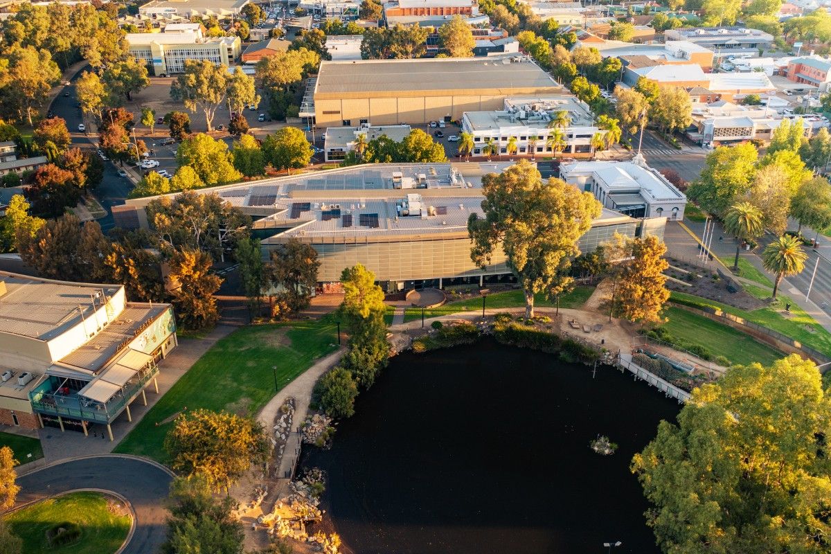 Aerial view of lagoon and two-storey glass and steel Wagga Civic Centre building.