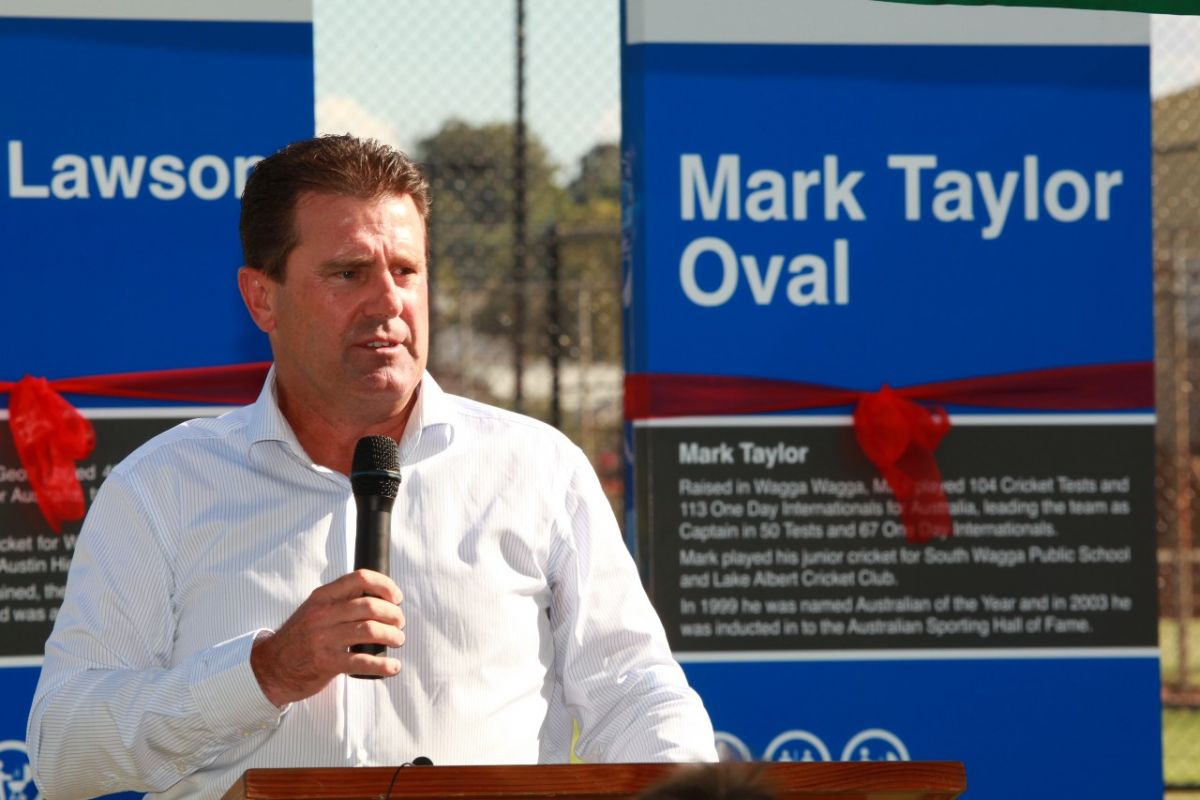 man speaking on microphone in front of sign