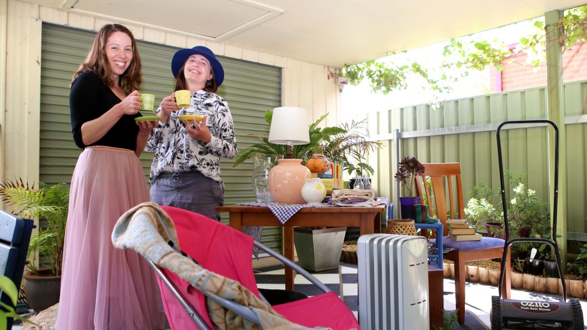 Two women standing beside table with bricabrac