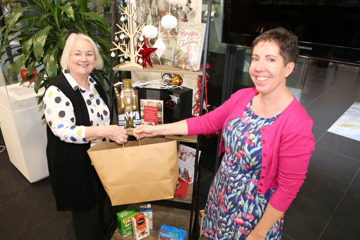 Two women, shelf with christmas decorations, non perishable food items