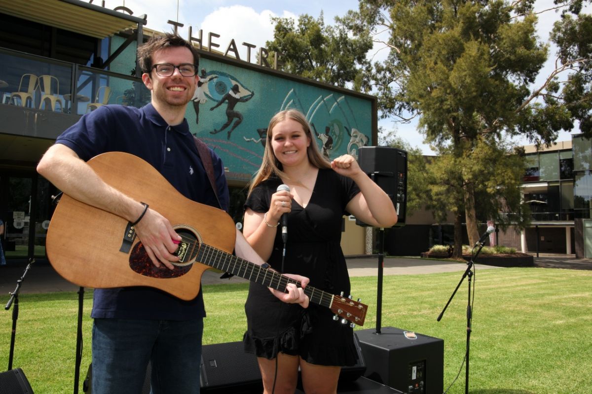 young man with guitar and woman with microphone surrounded by music kit