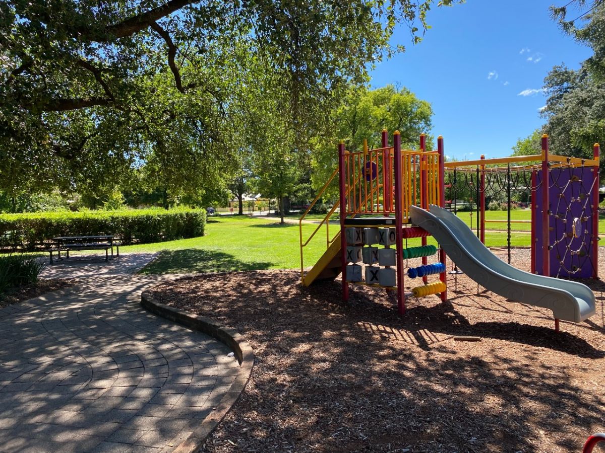 A large tree shades playground equipment