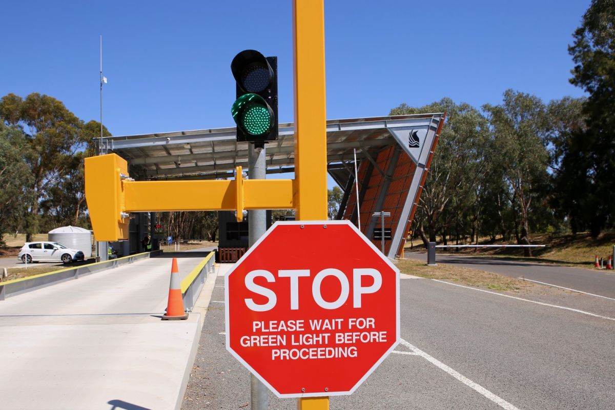 Stop sign and green traffic flow light in foreground with new weighbridge in background