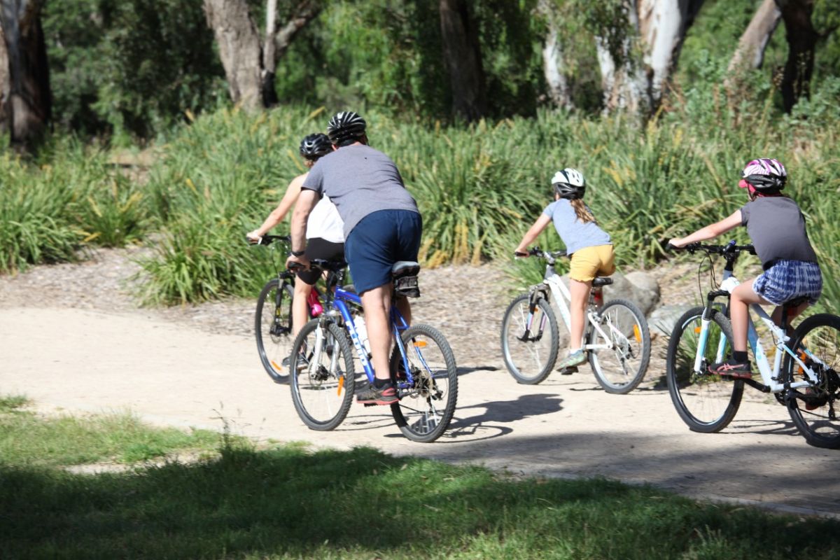 A group of adults and children cycle on a track