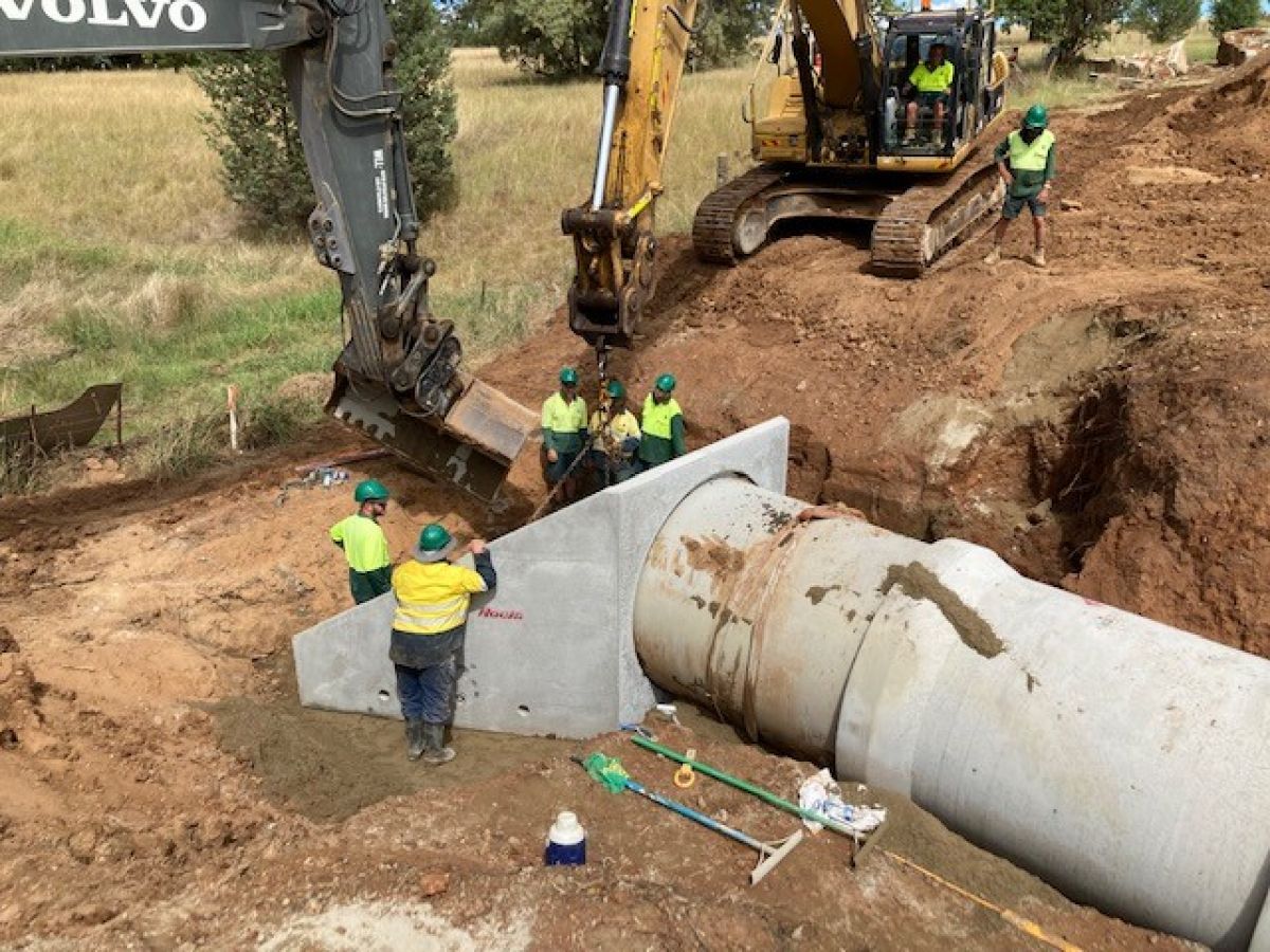A group of workmen standing beside an enormous concrete pipe