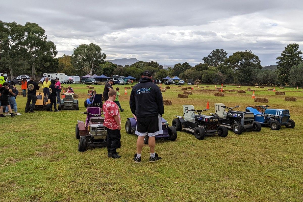 Man and teenager looking at ride on lawn mowers