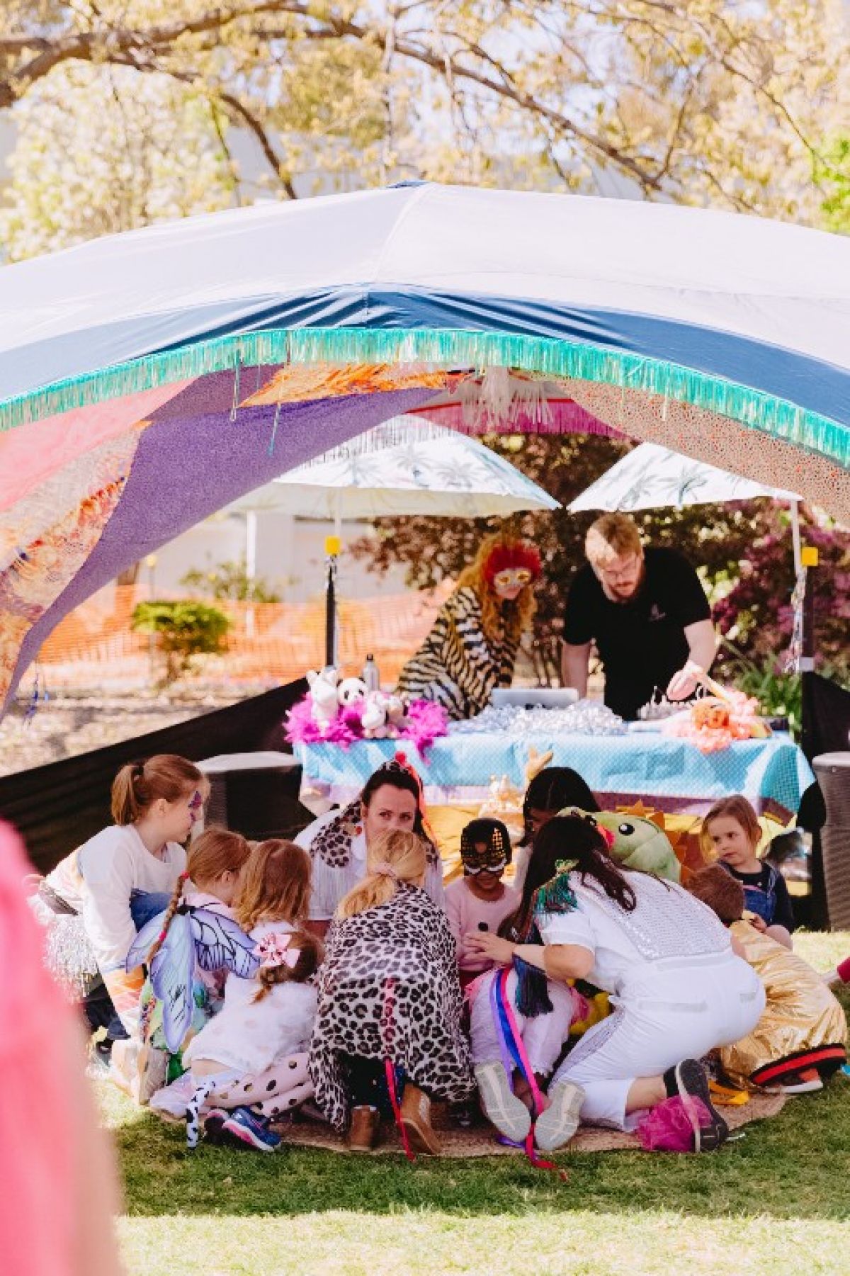 Kids and adults under shade tent at park