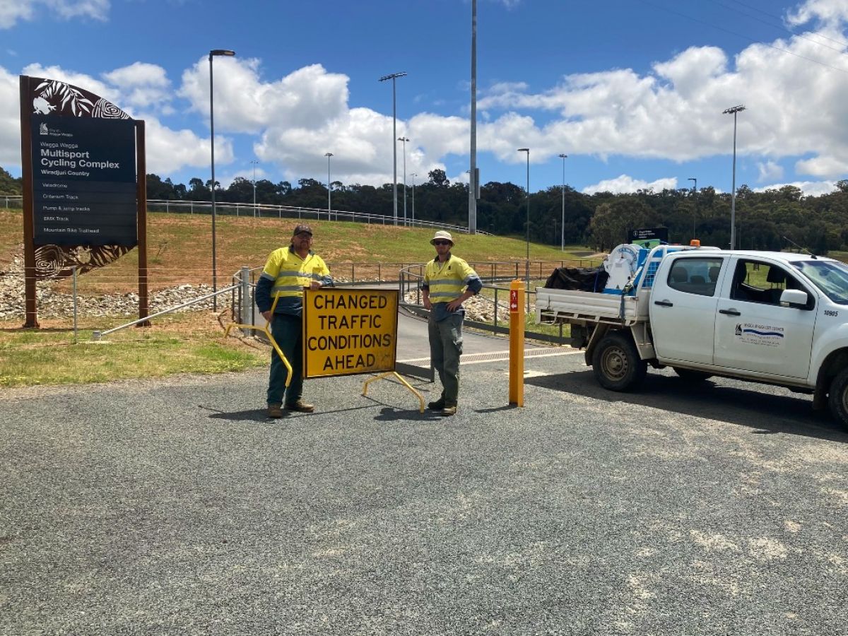 Two men stand beside a sign which reads 'changed traffic conditions ahead'