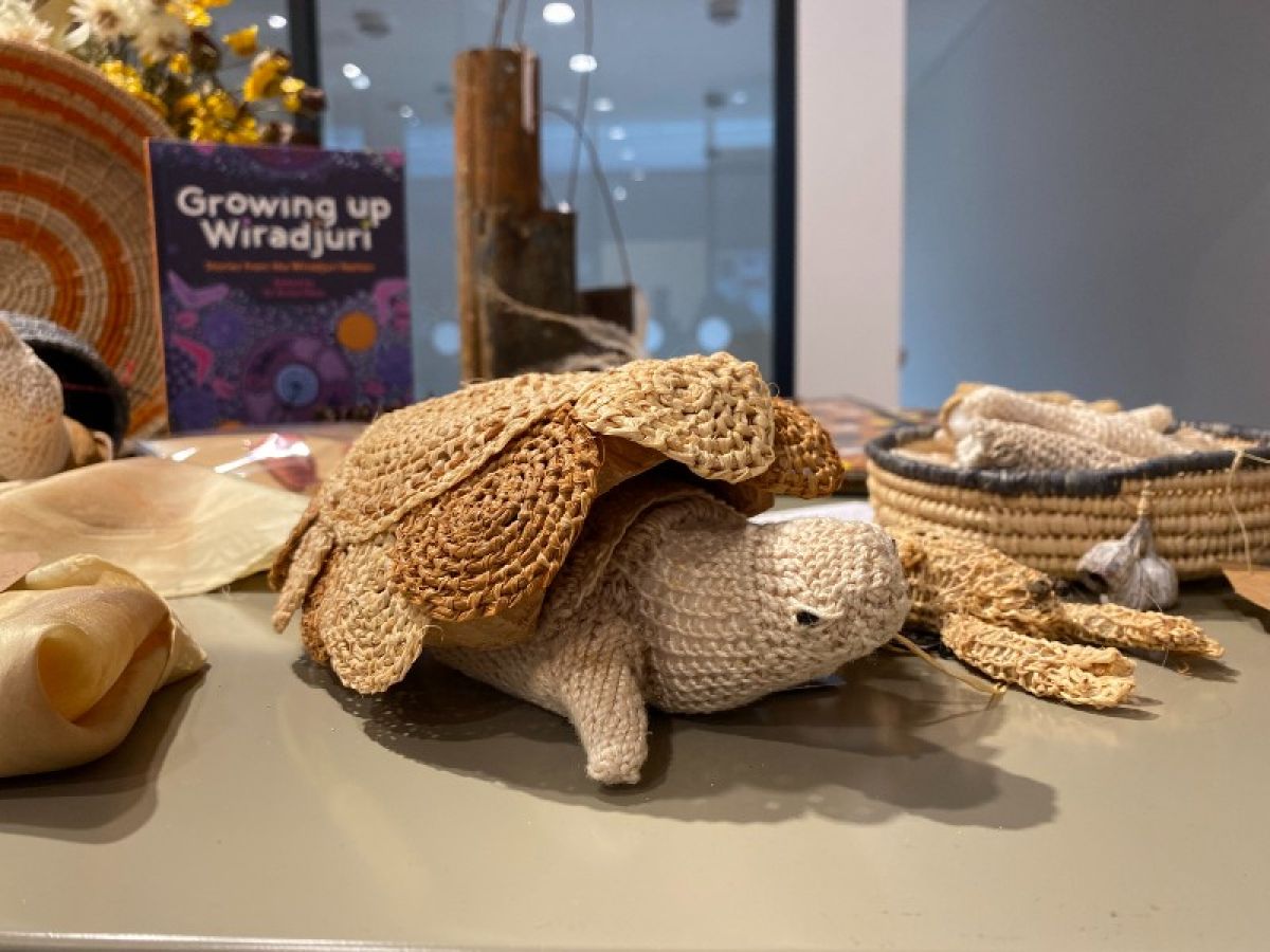 A woven turtle sits on a display