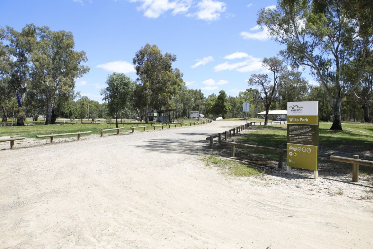 Gravel road entry to Wilks Park with camp ground sign in foreground on right