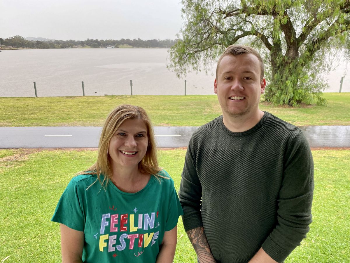 A woman and a man standing in front of a lake