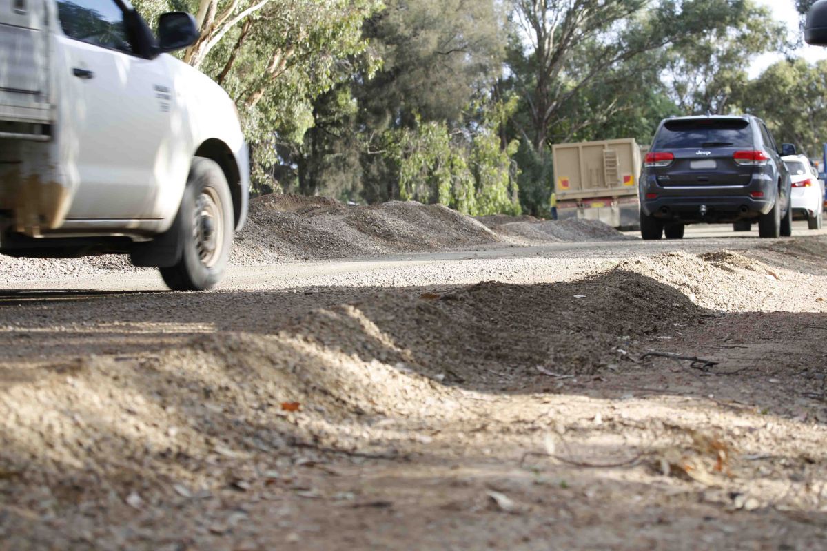 Cars driving past pile of gravel at road works