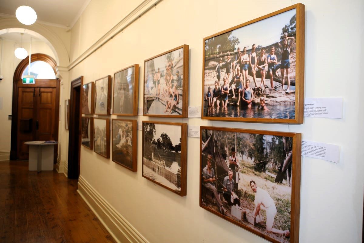 A hallway of an historic building with large framed photographs on the wall. 