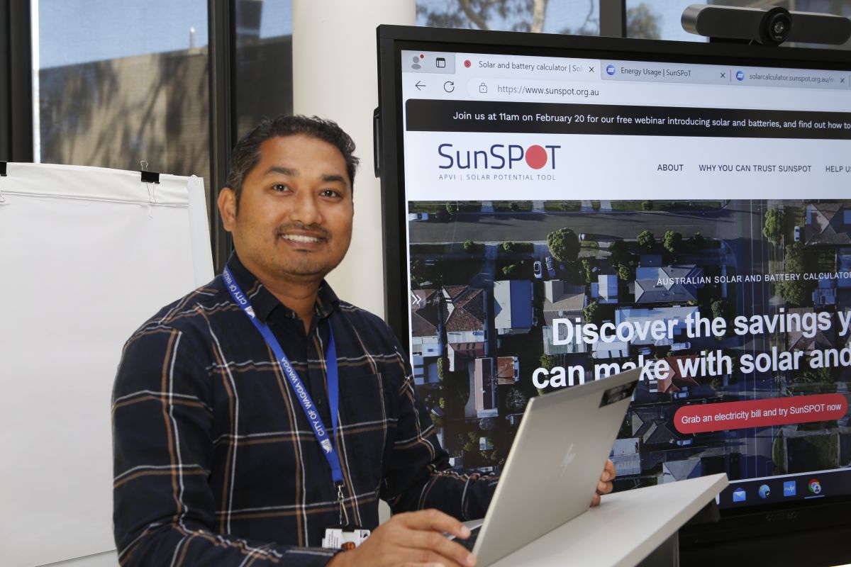 Net Zero Emissions Project Officer Hemendra Chaudhary smiling at camera in front of SunSPOT presentation.
