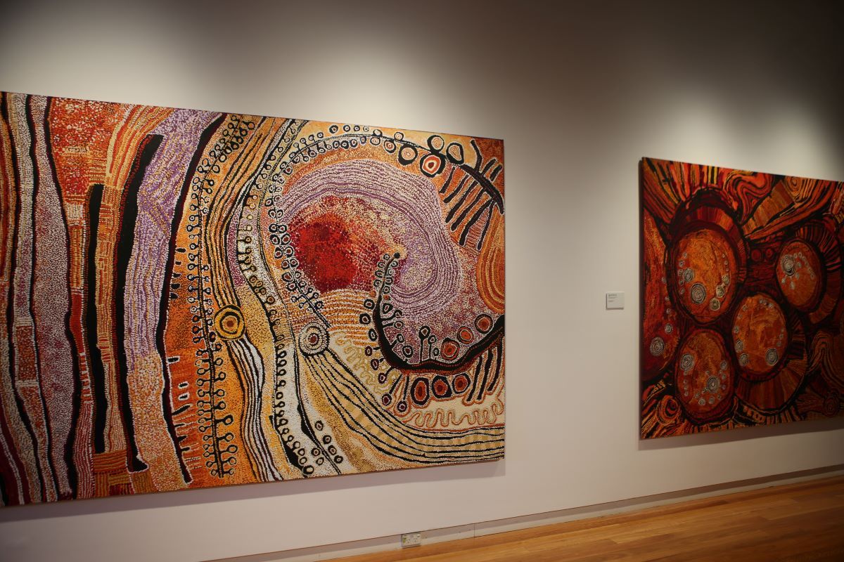 Two large Aboriginal artworks on an art gallery wall. 