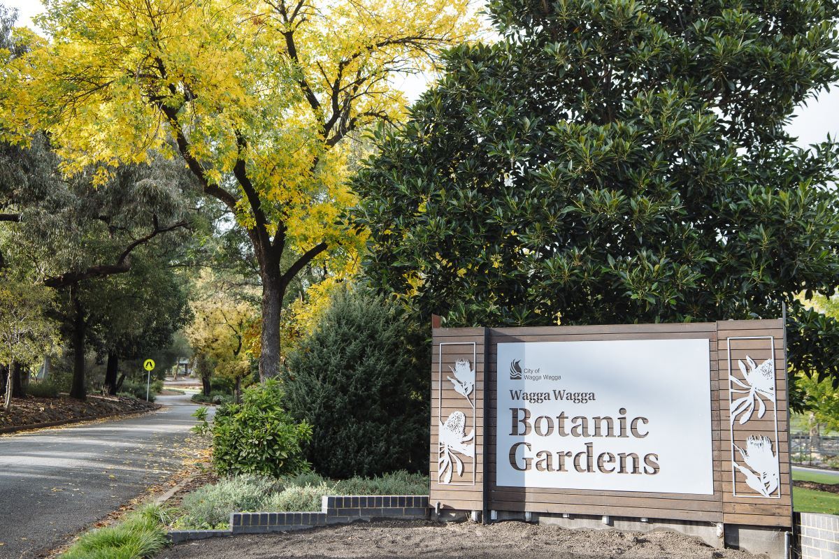 Wagga Wagga Botanic Gardens entrance sign with trees and road in background.