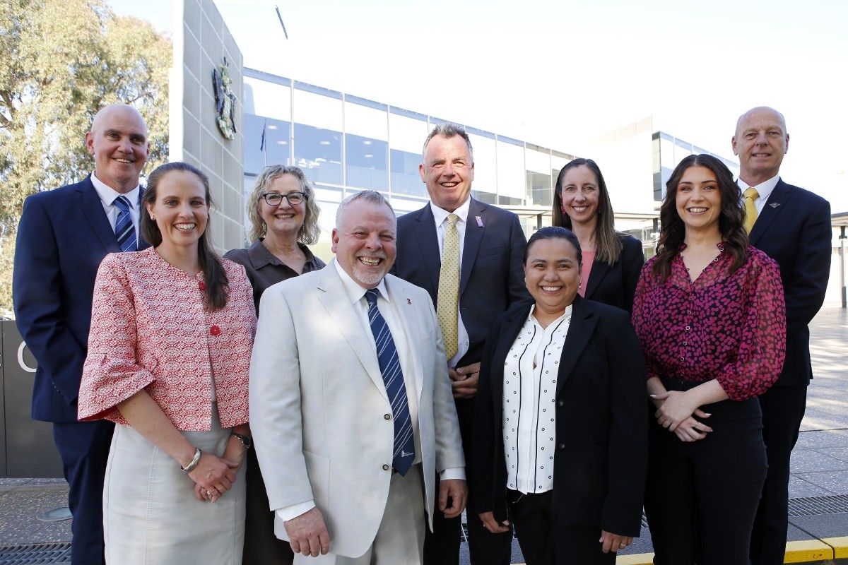 Five women and four man standing in two ranks in front of the Wagga Wagga Civic Centre.