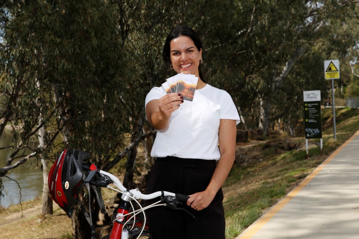 A women stands with a bike and holding a map.