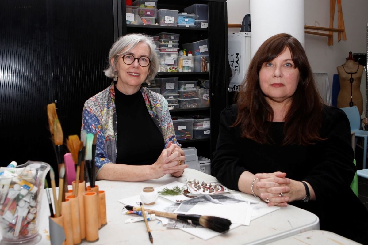 Two staff sit inside an art workshop.