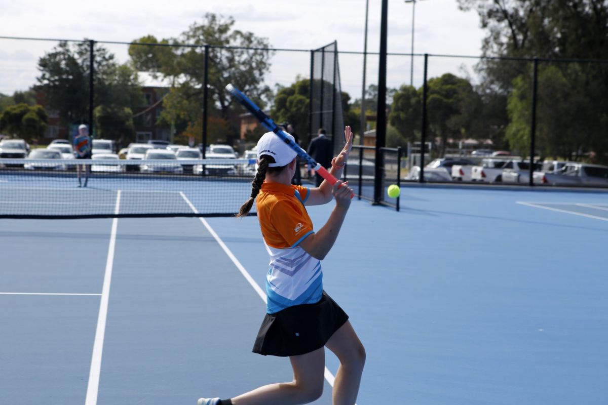 Female tennis player getting ready to hit the ball with her racquet.