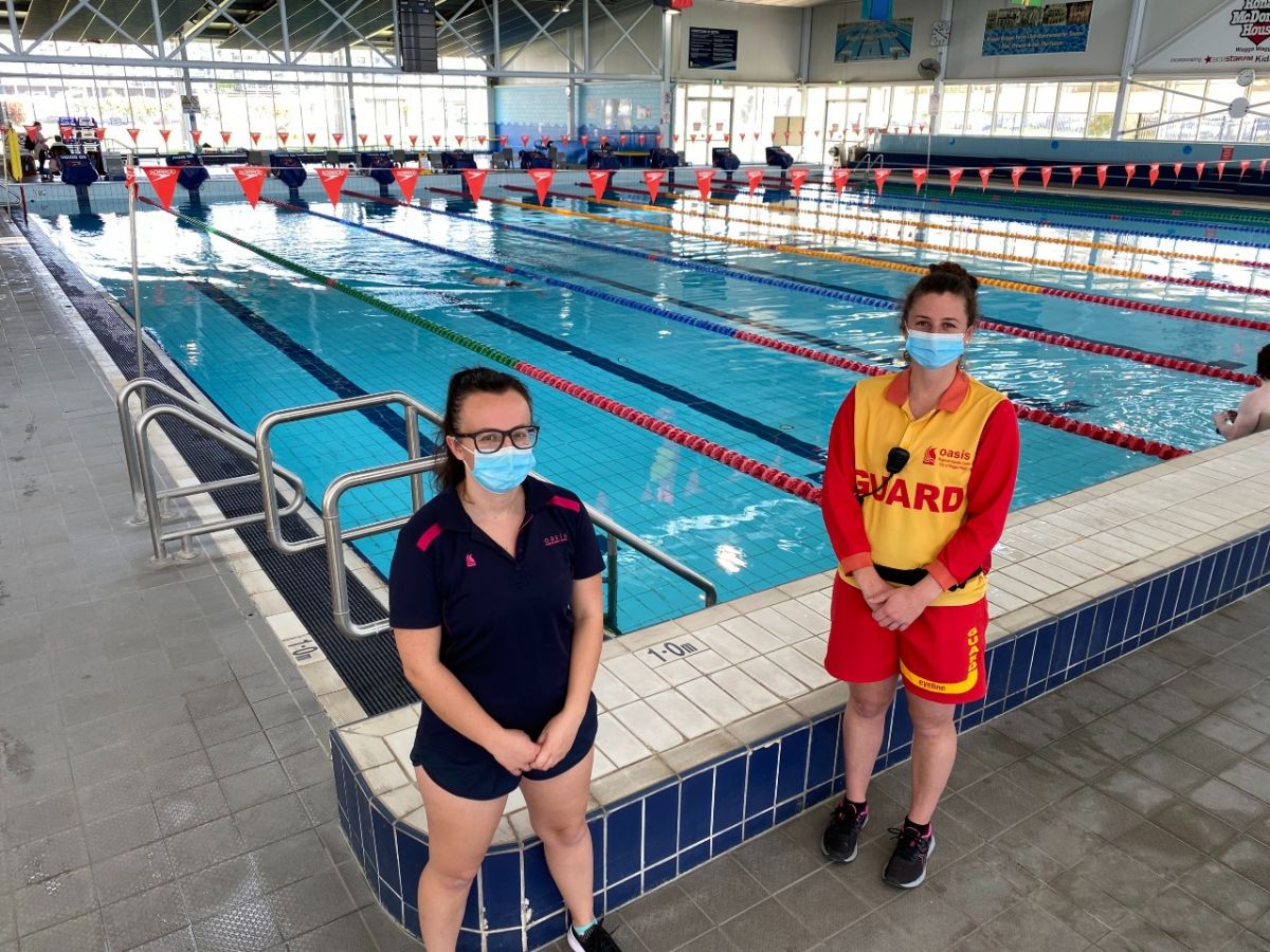 Two women stand beside an indoor pool