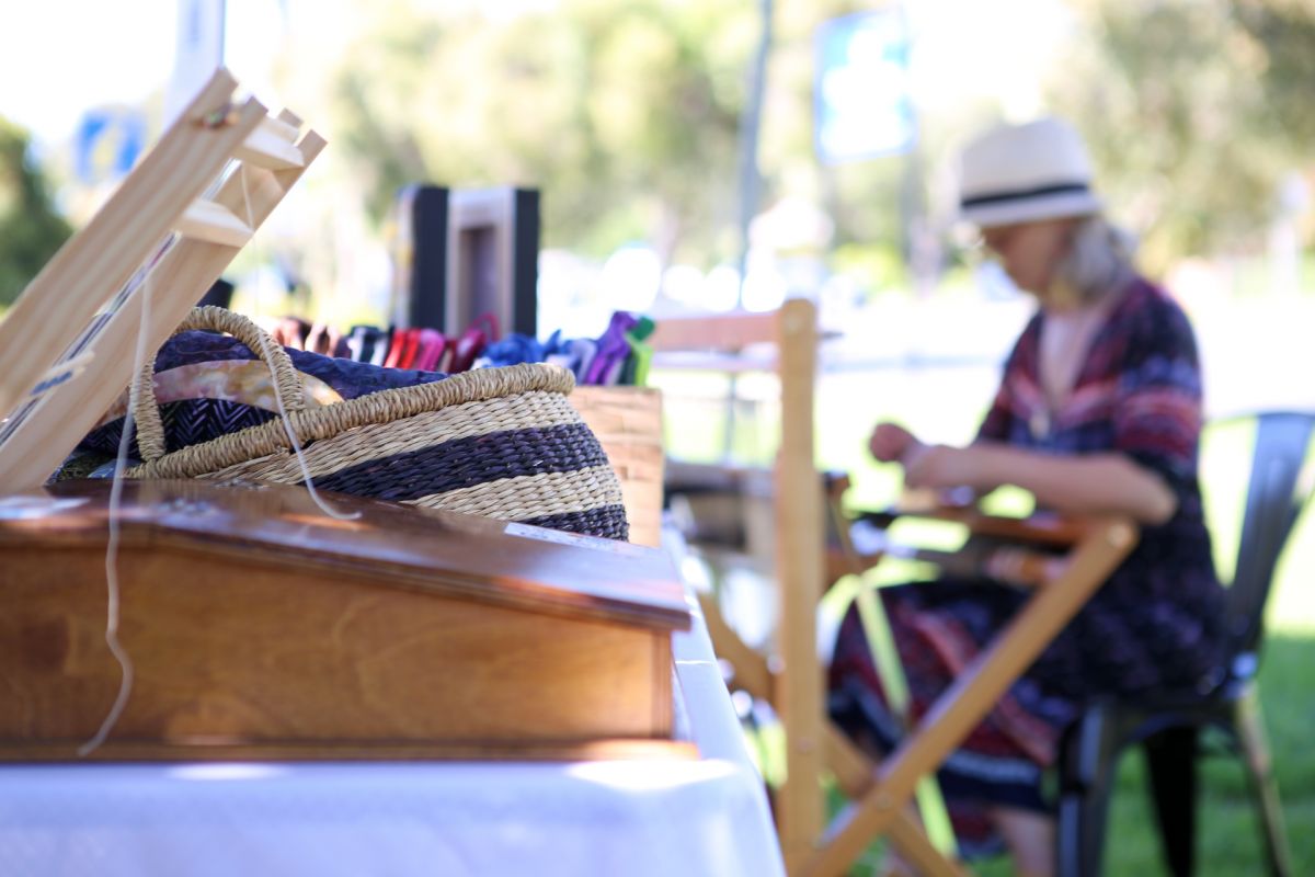 Woven alpace fleece products on table with woman sitting at loom in background