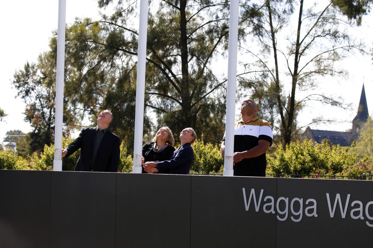 Two men, a woman and a school pupil raise flags