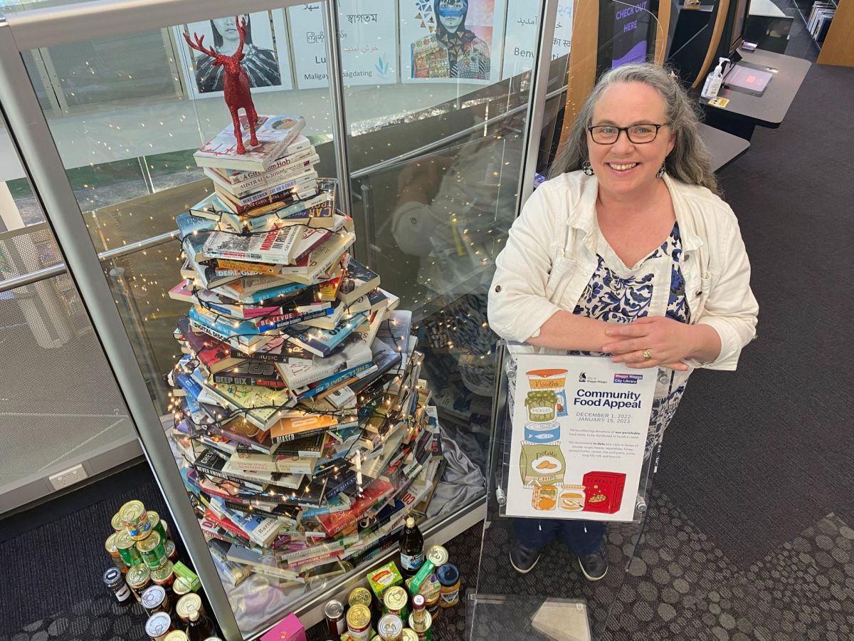 Woman standing beside Christmas tree made of books