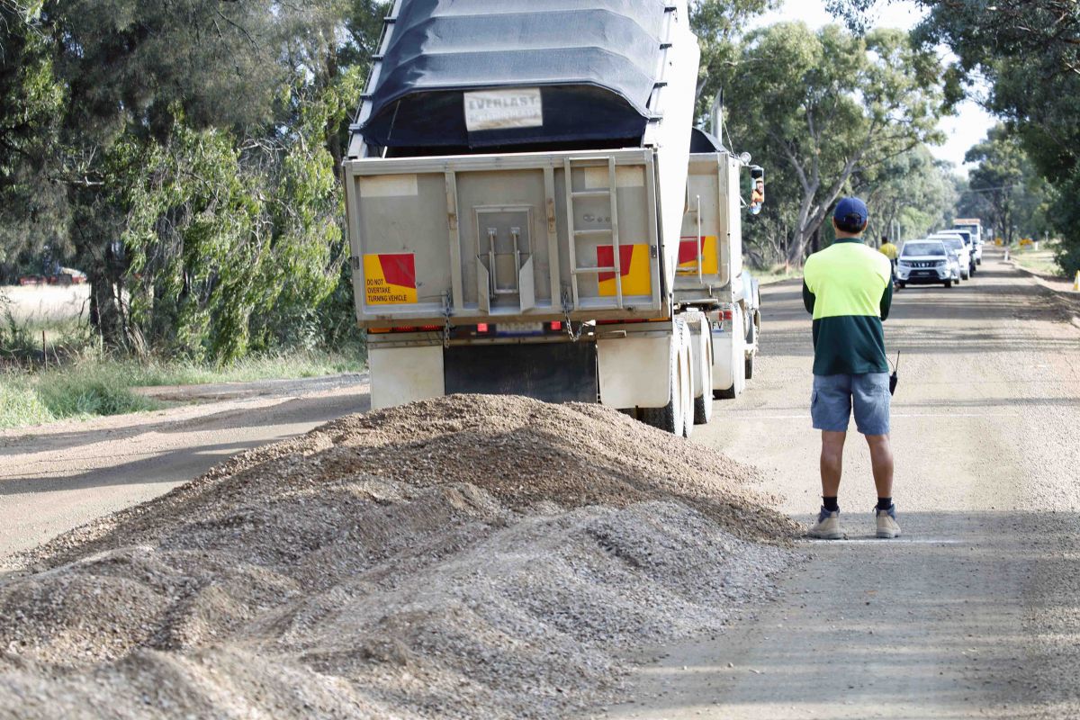 Truck dumping load of gravel at road works site