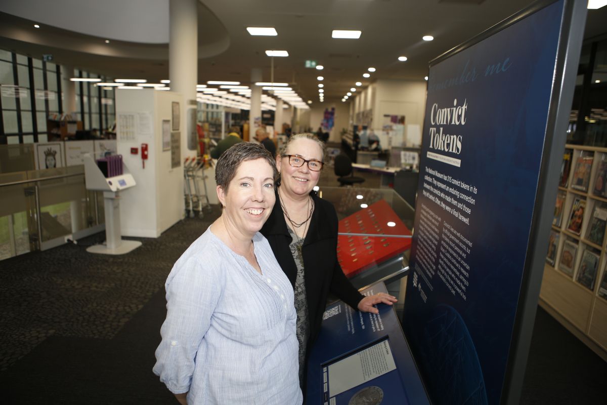 Two library staff (Wendy Harper and Christine Bolton) stand in front of exhibition and smile. 