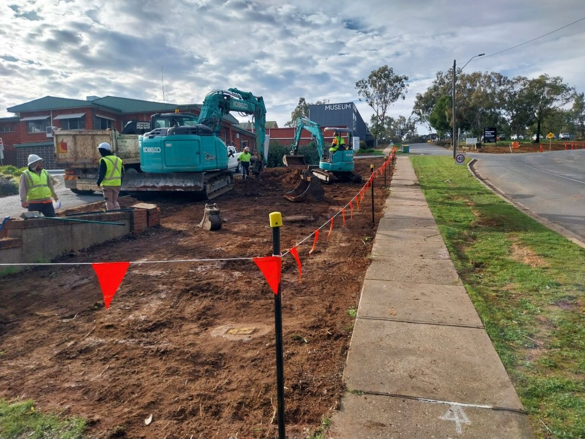 Road work plant and machinery and workers clearing road verge on Lord Baden Powell Drive