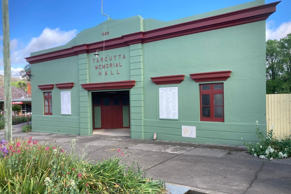 The facade of a cement building that was built in the 1920's. It is painted green with maroon trimmings. 