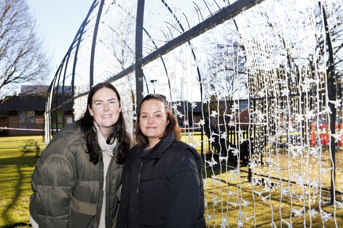 Two woman standing next to a light tunnel exhibit.