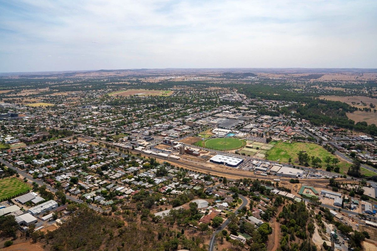 Aerial of residential suburb in foreground, with sporting grounds and CBD in background