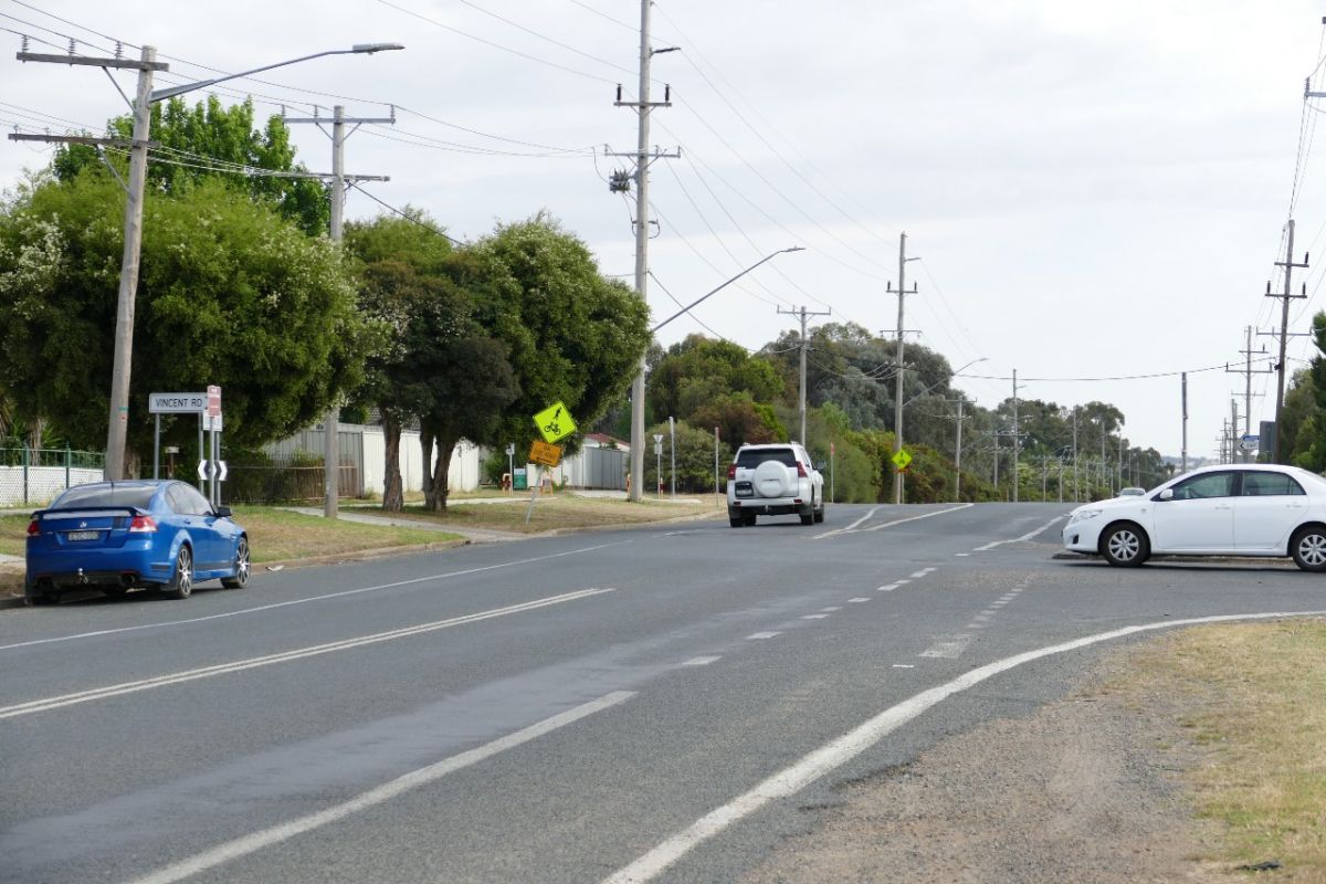 Traffic at T-intersection, with street sign for Vincent Road on the left