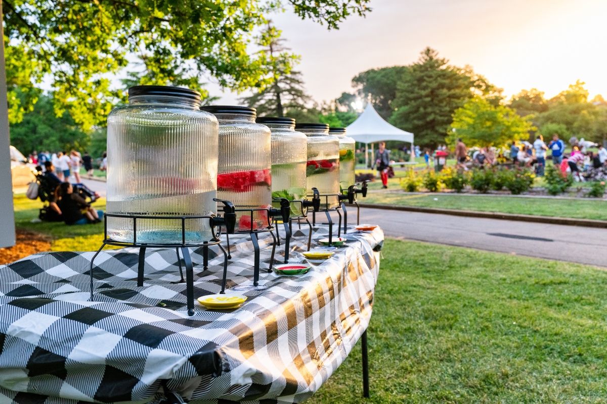 Table at Fusion Botanical 2023 laden with large fruit-water bottles for visitors.