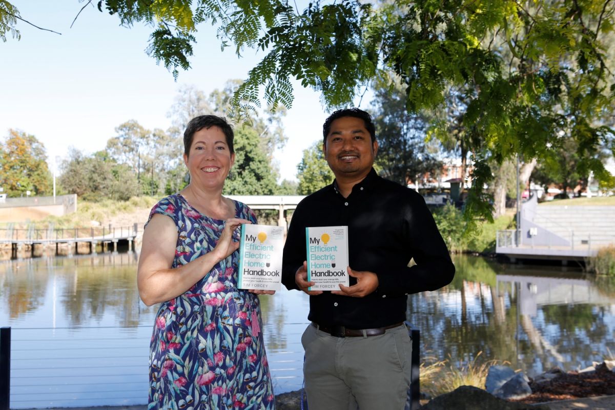 Two people standing outside holding books.