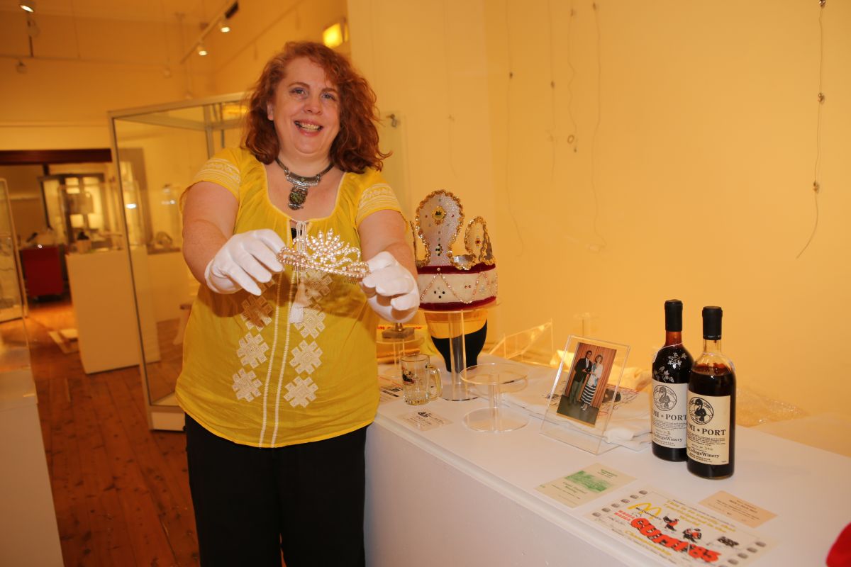 Woman holding a tiara, standing in exhibition gallery at museum