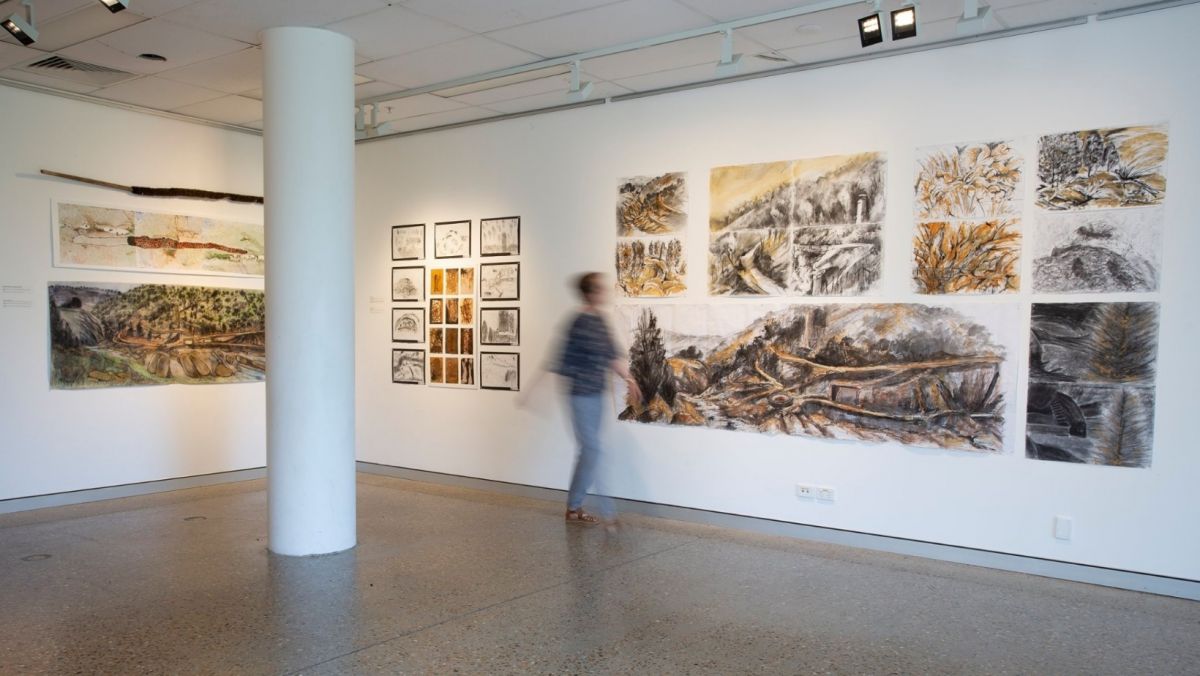 Art work on gallery wall with blurred image of person walking past