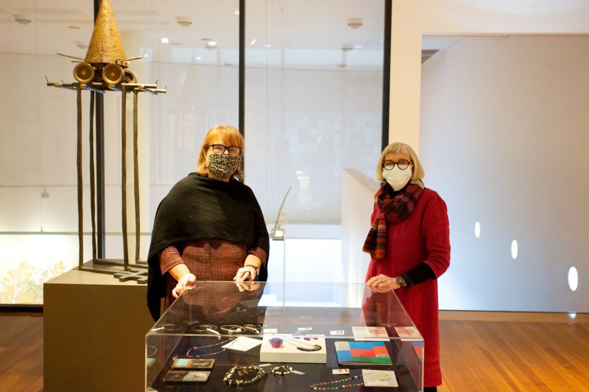 Two women standing behind display case at art gallery