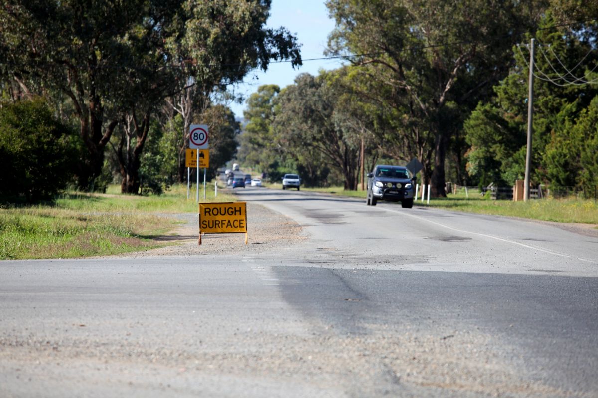 Rough Surface sign with road in foreground and background