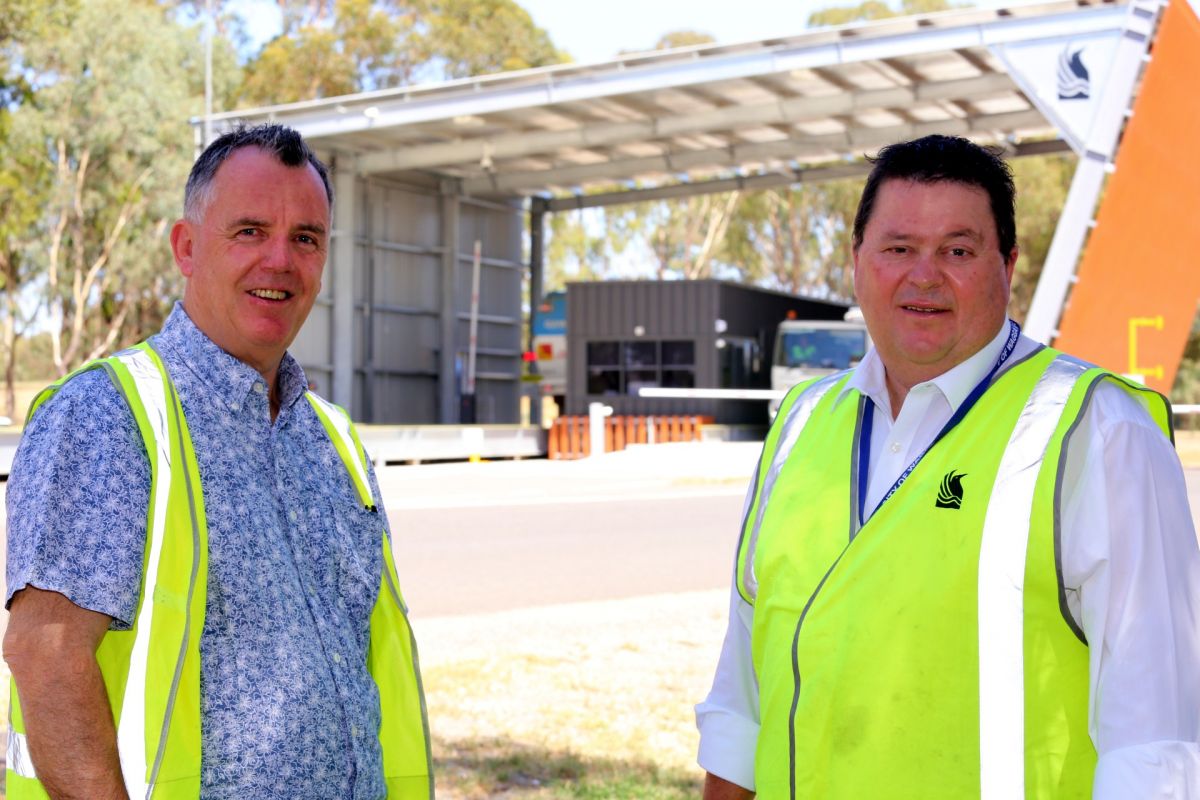 Two men in fluoro vests with weighbridge in background