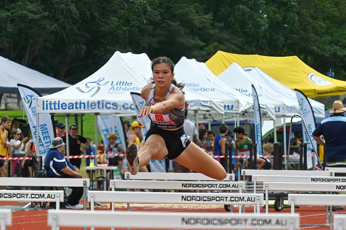 Head-on of female teenager hurdling